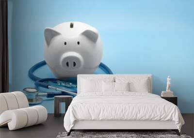 piggy bank with stethoscope isolated on light blue background with copy space. health care financial Wall mural