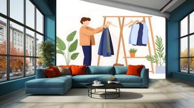 A person organizing clothes on a wooden rack, surrounded by potted plants, in a stylish, minimalistic setting. Wall mural