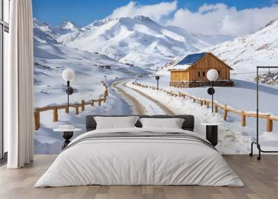 A serene winter landscape featuring a wooden cabin surrounded by snow-covered mountains and a winding road. Wall mural