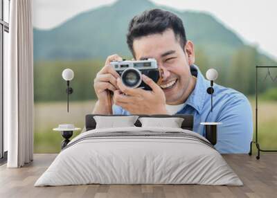 Asian photographer with vintage camera taking pictures in nature, lifestyle concept. Wall mural