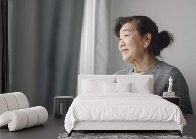 Asian senior woman drinking hot tea near window outdoor, lonely concept. Wall mural