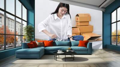 Asian woman packing goods with sticky tape for selling online, delivery concept. Wall mural