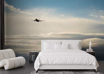 Silhouette airplane flying in the sky surround by blue cloud Wall mural