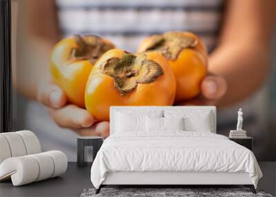 Hand holding persimmon fruit for giving Wall mural