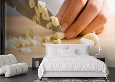 Woman chopping garlic on wooden board for cooking Wall mural