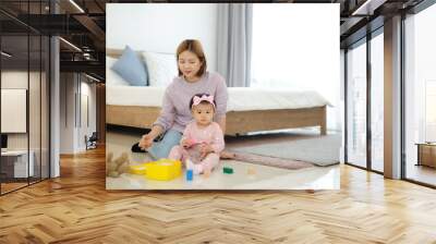 Adorable smiling little girl playing with toys with her mother on the bedroom floor. Wall mural