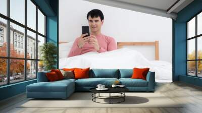 Handsome man using mobile phone after wake up on the bed,concept wake up,relax and lifestyle Wall mural