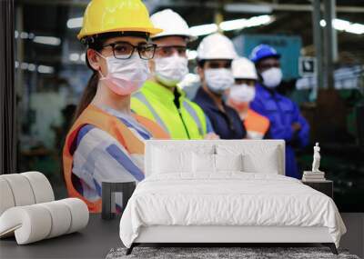 Industrial woman engineer or factory worker wearing helmet and hygiene face mask with men stand in line at manufacturing plant.People working industry during covid pandemic. Wall mural