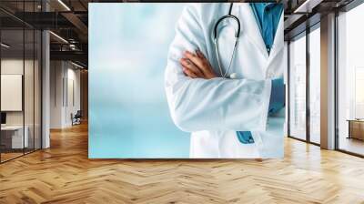 Doctor in white coat standing arms crossed, holding stethoscope, halfbody shot, light blue blurred background, professional medical scene Wall mural