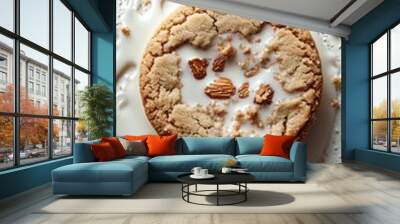 A single almond cookie sits on a white surface with almond slices, white milk, and sugar crumbs around it. Wall mural