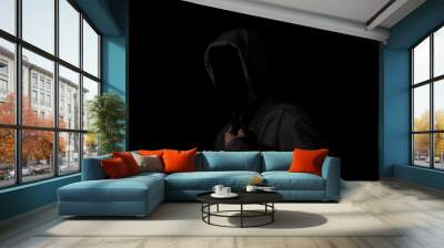 Scary and creepy man hiding in the shadows, with the face and identity hidden with the hood, Dark mysterious man in hoodie on black background. copy space. Concept for fear, mystery, danger, hacker. Wall mural