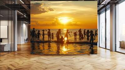 Silhouetted scene of golden sunset sky at crowded beach which people and family play and swim together. Wall mural