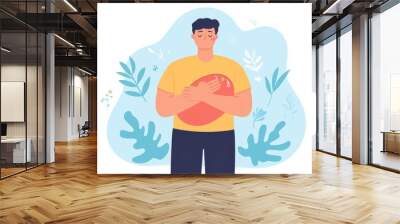 A man holding his heart, surrounded by leaves. Wall mural