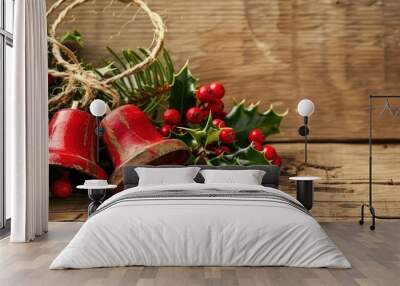 Christmas bells and holly on a wooden background, perfect for holiday messages. Wall mural