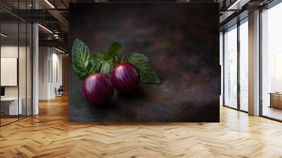 Two purple-striped tomatoes with green leaves on dark grey background Wall mural