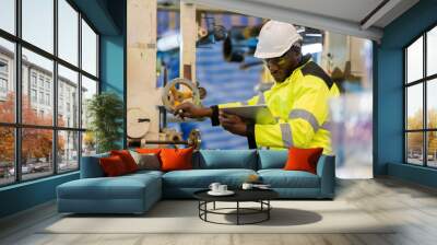 african engineer Controlling work via tablet Wear uniforms and helmets. Operates a hand crank machine while working on steel and plastic production. working in an industrial factory Wall mural