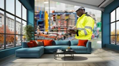 African male engineer standing in engine room Using a laptop to control a material production machine system, working in a plastic and steel industry regarding the company's product business. Wall mural