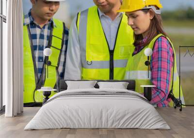 Close-up shot of female engineer, 2 male engineers by side, checking work on laptop, meeting about design, architecture, construction business project industry Wear a helmet and a vest. Wall mural