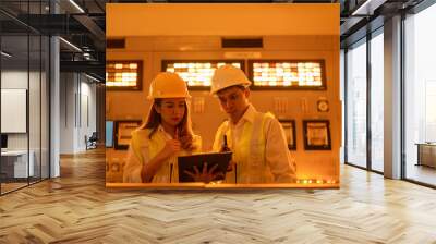 In the middle of the operating room, there were two male and female Asian engineers at the executive level checking the systems in the control room of an industrial nuclear power plant. using a laptop Wall mural