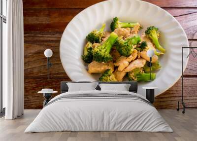 Stir fried broccoli and chicken in white plate on wooden table. Wall mural