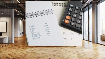 Expense and budget concept, list of expense in small notepad and calculator on desktop calendar on wooden table Wall mural