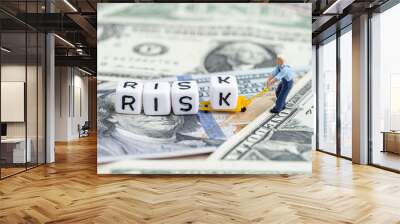 Investment risk in stock market or financial assets concept, miniature people man pulling forklift with cube small block building the word Risk on pile of US Dollar banknote money Wall mural