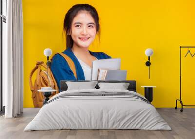 Happy asian female college student smiling at camera on yellow background and copy space, holding tablet and text books, hanging bagpack. Youth girl student look clever and smart. education concept Wall mural