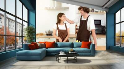 Happy couple preparing food having fun together Man girl standing in kitchen at home on first dating Spouses enjoy warm conversation and cooking process Care for health They are looking each other Wall mural