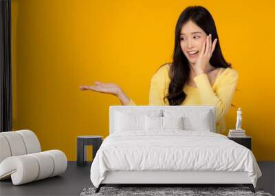 Happy surprised young asian woman with isolated on yellow background holding copy space imaginary on beauty palm for insert advertisement, happiness and smile face Attractive beautiful girl portrait Wall mural