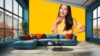 Portrait young asian woman look at copy space Beautiful girl wear yellow T shirt with yellow background at studio Pretty asia female get confident. Female get satisfied something Lovely lady get happy Wall mural