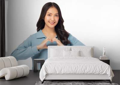 Smiling young asian woman showing heart gesture by using two hands and looking at camera  Wall mural