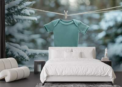 A cozy green baby onesie hanging on a clothesline amidst a snowy winter landscape, showcasing comfort and warmth. Wall mural