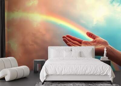 A hand reaching toward a vibrant rainbow against a dramatic sky, symbolizing hope and connection with nature. Wall mural