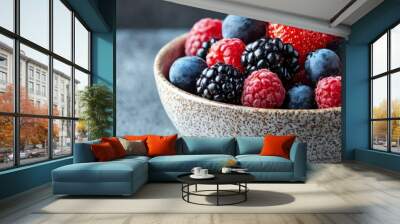 Fresh assorted berries in a textured bowl, perfect for healthy eating and vibrant food photography. Wall mural