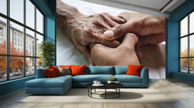 .Hands of the old man and a man hand on the white bed Wall mural