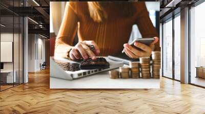 accountant working on desk in office using calculator and smartphone to calculate budget. concept finance and accounting in morning light Wall mural