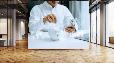 Asian Man are putting coins in a piggy bank for a business that grows for profit and saving money for the future. planning for retirement concept Wall mural