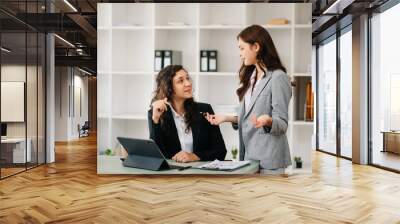 Business colleague business presents and explains and using laptop and tablet. Teamwork, financial marketing team, while sitting in office Wall mural