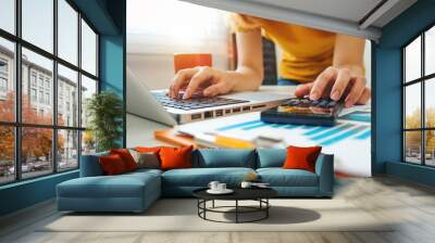 businesswoman hand working with finances about cost and calculator and laptop with tablet on withe d Wall mural