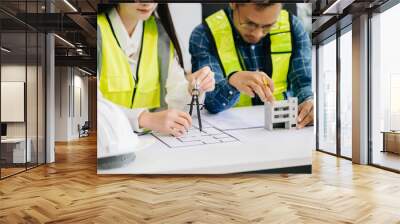 Engineer teams meeting working together wear worker helmets hardhat with on architectural project site and making model house. Asian industry professional team Wall mural