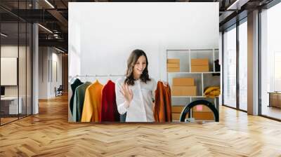 Fashion blogger concept, Young Asian women selling clothes on video streaming.Startup small business SME, using smartphone or tablet taking receive and checking. Wall mural