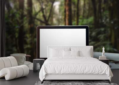 Front view of cup and laptop, smartphone, and tablet on table in forest Wall mural