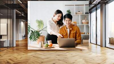 Two Asian business workers talking on the smartphone and using laptop at the home office. Wall mural