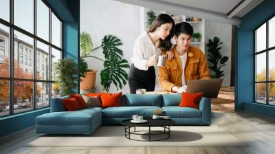 Two Asian business workers talking on the smartphone and using laptop at the home office. Wall mural