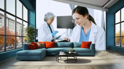 Two scientist or medical technician working, having a medical discuss meeting with an Asian senior female scientist supervisor in the laboratory with online reading, test samples and innovation Wall mural