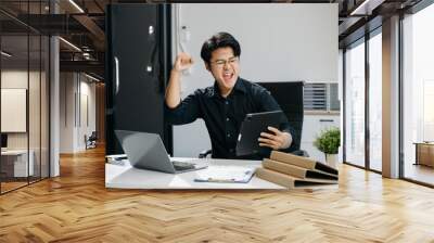 Young business man working at office with laptop, tablet and taking notes on the paper.. Wall mural