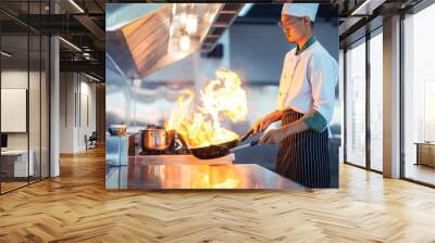 Chef in restaurant kitchen at stove and pan cooking flambe on food Wall mural