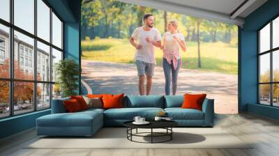 Portrait of Young couple running in the park at sunset. Concept sport and love. Warm tone. Wall mural