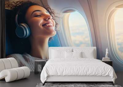 A joyful woman, comfortably seated on a plane, listening to music on her wireless headphones, with a cheerful look Wall mural