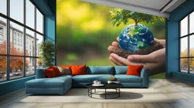 Human hands gently holding a flourishing tree and Earth globe, with a green nature backdrop, celebrating Earth Day and the importance of global environmental care Wall mural